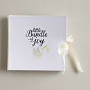 Front angle of a white baby photo album with the words 'Little Bundle of Joy' on the front
