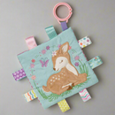 A Mary Meyer Taggies Crinkle Me Flora Fawn sensory toy, featuring a fawn character on a blue background with colorful flowers and leaves, attached to a pink loop clip.